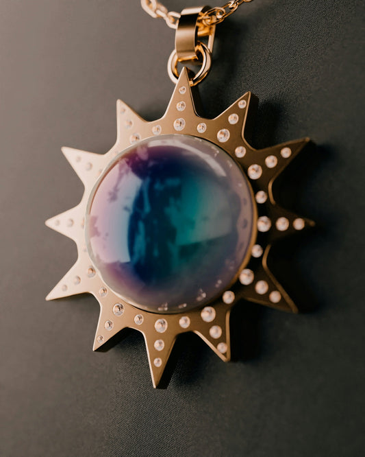 Gold sun pendant with colorful gemstone center.