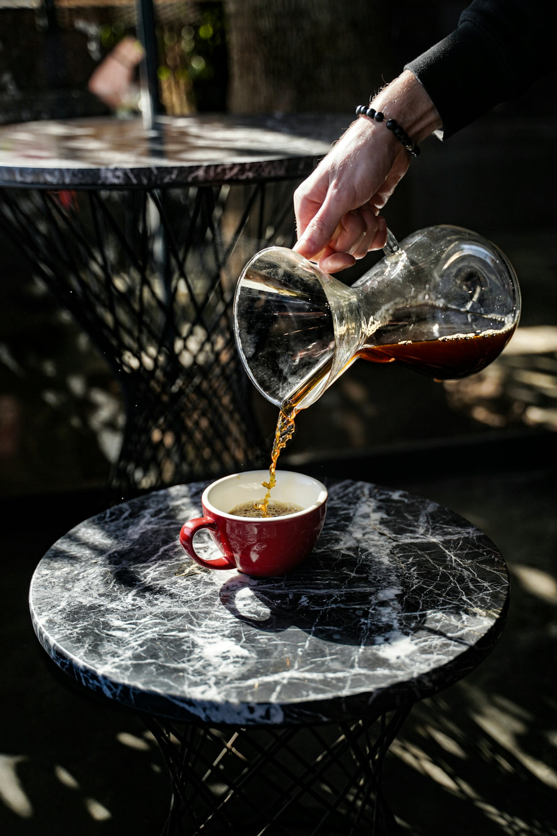 Coffee is being poured into a red cup.
